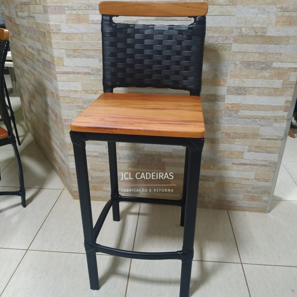 Foto de um conjunto de cadeiras de bar alinhadas, com assentos de madeira em peroba rosa e estrutura metálica preta, posicionadas ao lado de uma bancada. A marca "JCL CADEIRAS" é visível sobre a imagem.